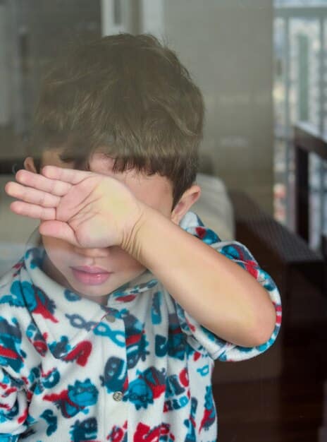 A close-up of a child's hands nervously fidgeting. The child looks anxious and avoids eye contact.