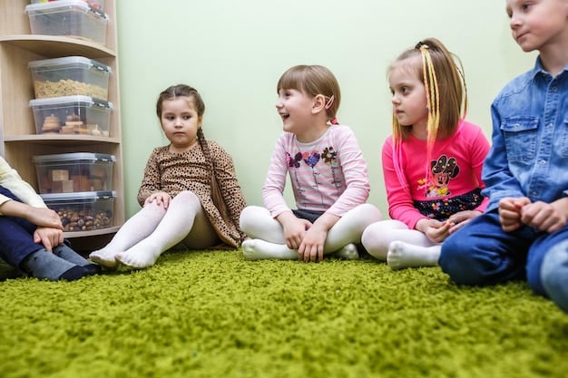 Three young children are sitting in a circle on a colorful rug, participating in a lively group discussion. One child is holding a microphone, while the other two are listening attentively and raising their hands to speak. The background shows shelves filled with books and educational toys.