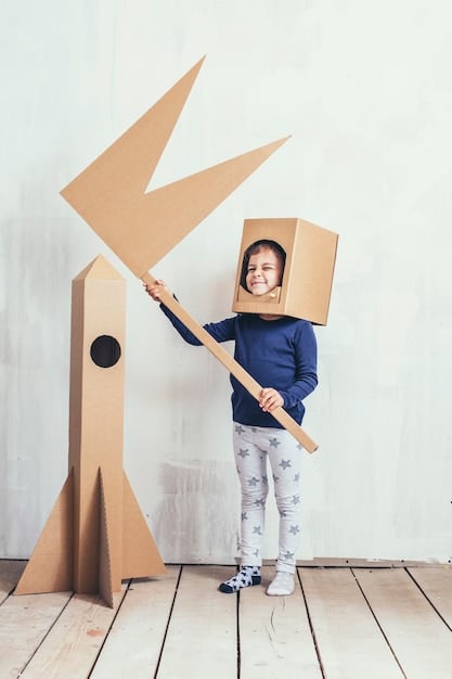 A child proudly standing next to a elaborately decorated cardboard box castle, complete with paper flags, painted turrets, and a drawbridge made of string. The child is smiling, showcasing their creative accomplishment.