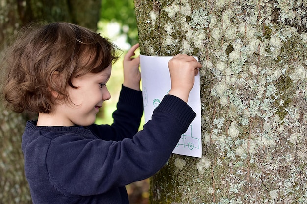 A close-up photo of a child's hands holding a nature scavenger hunt checklist. The list includes items like 