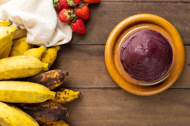 A close-up shot of various colorful fruits and vegetables (berries, spinach, bananas, mangoes) arranged around a blender on a wooden kitchen counter, suggesting ingredients for a healthy smoothie.