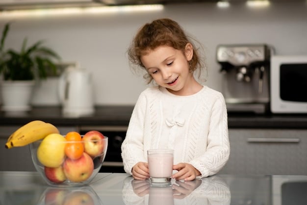 A child happily drinking a green smoothie with a straw, sitting at a kitchen table with a bowl of colorful fruits beside them, conveying a sense of enjoyment and health.