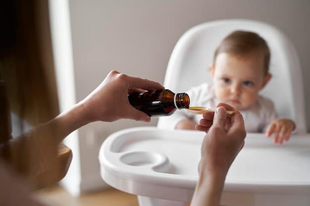 A close-up of a baby's hand holding a dropper filled with liquid Vitamin D supplement. The background is a softly focused image of a parent's hand supporting the baby.