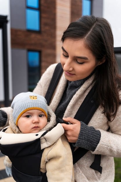 A mother adjusting the straps of a soft-structured baby carrier while holding her baby. The focus is on the adjustability features of the carrier, such as buckles, straps, and snaps.