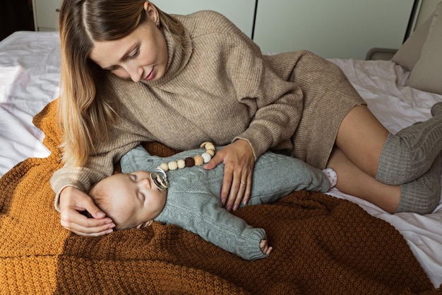 A mother holding her baby in the colic carry position, supporting the baby's head and abdomen. The baby appears relaxed and comfortable in this position.