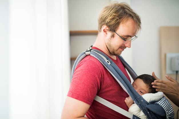 A parent checking the baby's position in the carrier. The parent is using their hand to make sure the baby's airway is clear and that the baby is comfortable. They are indoors, with natural light coming through a window.