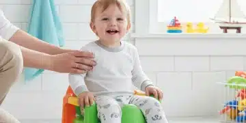 Toddler smiling on a colorful potty chair with parent's gentle guidance, symbolizing successful potty training.
